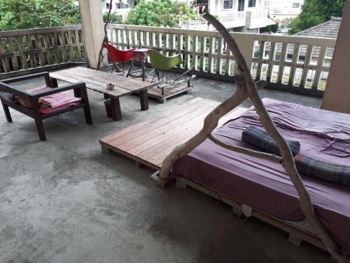 a porch with a bed and a table and chairs at backpackers guesthouse Border in Nago