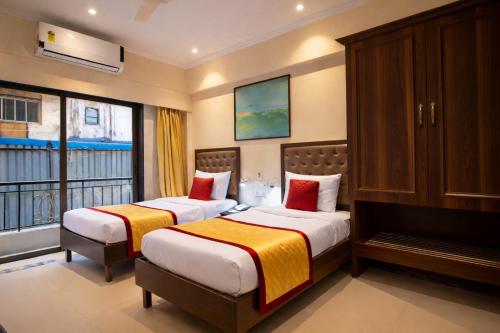 two beds in a hotel room with a balcony at West End Hotel Opp Bombay Hospital in Mumbai