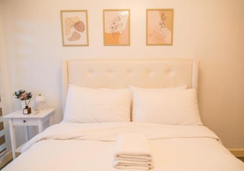 a bedroom with a white bed with three pictures on the wall at Relaxing Mountain View 2BR Fast WiFi and PS5 in Manila