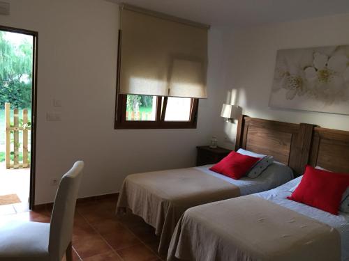 Habitación de hotel con 2 camas con almohadas rojas en Alojamiento Mesón el Pozuelo en Tarifa