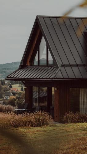 a house with a metal roof on top of a field at oto.domki in Rokiciny Podhalanskie