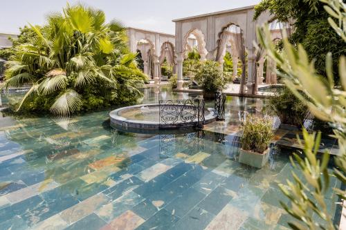 a courtyard with a fountain in a building with palm trees at Palais Namaskar in Marrakech
