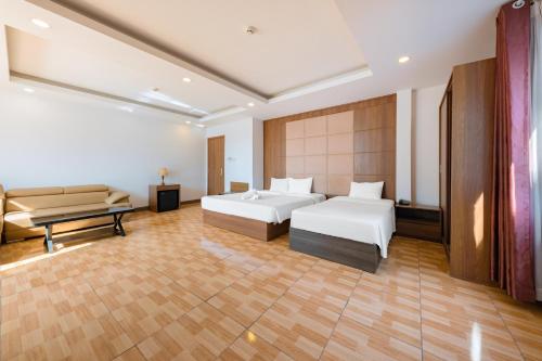 a hotel room with two beds and a couch at Dolphin Bay Hotel Nha Trang in Nha Trang