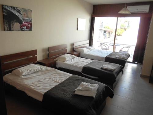 three beds in a room with a window at Ayia Napa Apartment in Ayia Napa