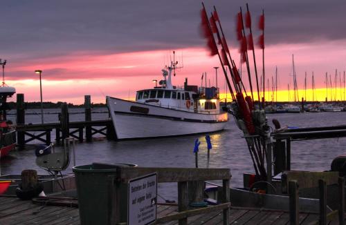 a boat is docked at a dock with a sunset at Hotel Sonneninsel Fehmarn in Fehmarn
