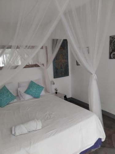 a bedroom with a white bed with a canopy at Jimbaran room 01 in Jimbaran