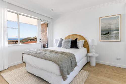 a white bedroom with a bed and a window at Medusa Bondi in Sydney