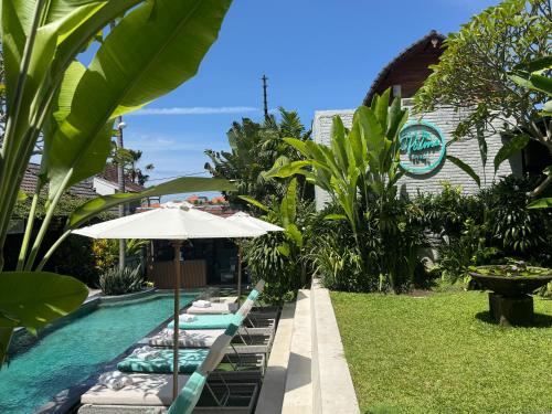 a swimming pool with lounge chairs and an umbrella at The Palms Canggu in Canggu