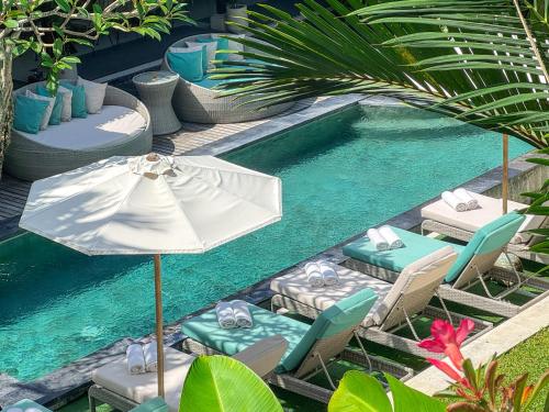 a pool with chairs and an umbrella and a swimming pool at The Palms Canggu in Canggu