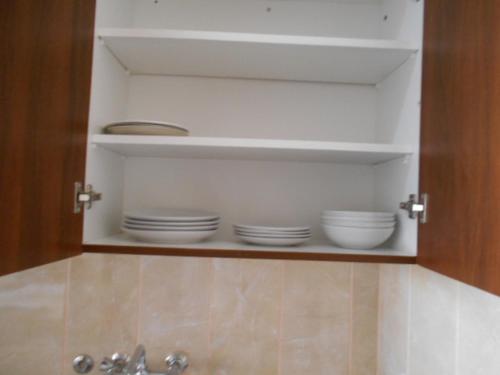 a cupboard with plates and dishes in it at Ayia Napa Apartment in Ayia Napa