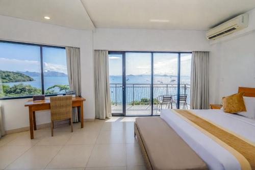 a hotel room with a bed and a desk and windows at Laprima Hotel in Labuan Bajo