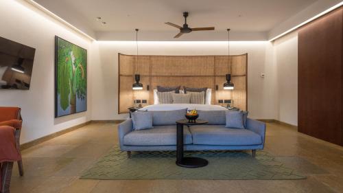 a bedroom with a bed and a blue chair and a table at Amaaranth Goa in Varca