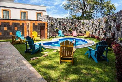 阿特利斯科的住宿－Soleil Inn Atlixco，一群椅子坐在游泳池附近的草地上