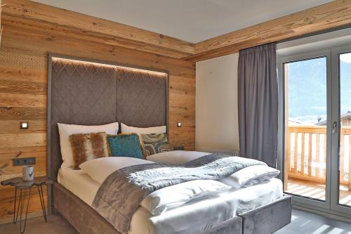 a bedroom with a large bed with a large window at Sieglhub Chalets - Appartements - Hotel in Flachau