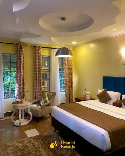 a hotel room with a large bed and a chair at Ufanisi Resort - Kisii in Kisii