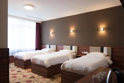 2 bedden in een hotelkamer met witte lakens bij Hotel King's Court in Amsterdam