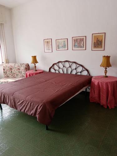a bedroom with a large bed with red sheets and two tables at Villa Rosa in Rapallo
