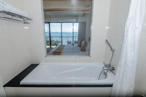 a white bath tub in a bathroom with a mirror at Laprima Hotel in Labuan Bajo