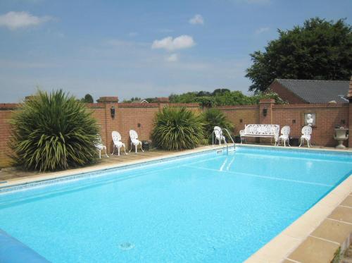 a swimming pool with white chairs and a table at Old Rectory Hotel, Crostwick in Norwich