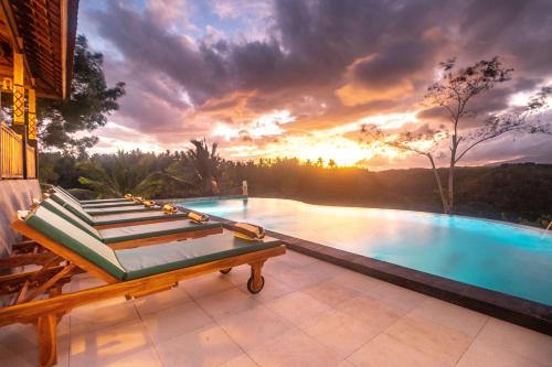 a pool with a bench and a sunset in the background at Green Coco Suite by AGATA in Nusa Penida