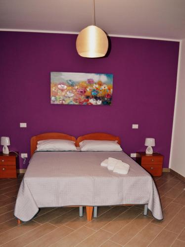 a bedroom with a bed with a purple wall at B&B Federico II in San Cipirello