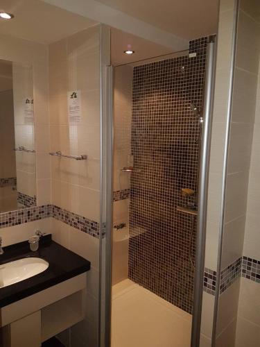 a bathroom with a glass shower and a sink at Apartments Konaci BOOKING in Kopaonik