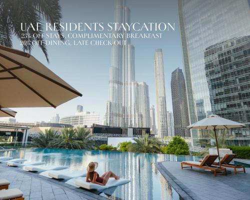 a woman sitting in a chair next to a swimming pool at Kempinski The Boulevard Dubai in Dubai