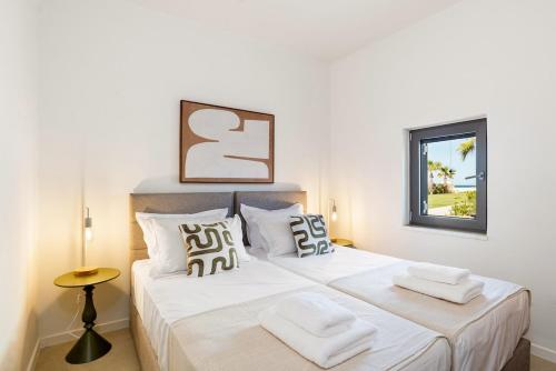 a bedroom with a bed with white sheets and a window at The Palms Seaside - Kolymvari in Kolymvari