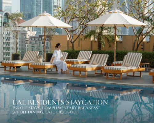 a woman sitting in lounge chairs next to a pool at Kempinski Central Avenue Dubai in Dubai