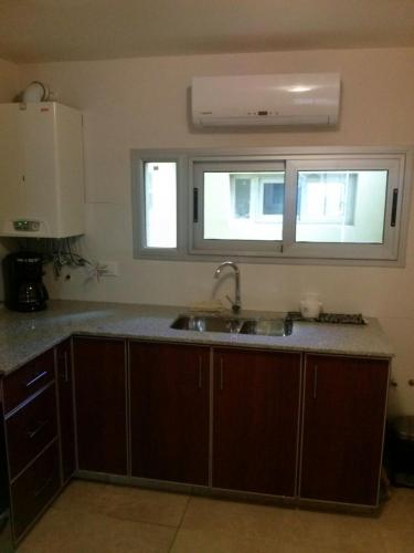 a kitchen with a sink and two windows at Bahiaxdia Fitz Roy 140 in Bahía Blanca