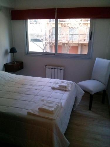 1 dormitorio con 1 cama, 1 silla y 1 ventana en Bahiaxdia Fitz Roy 140 en Bahía Blanca