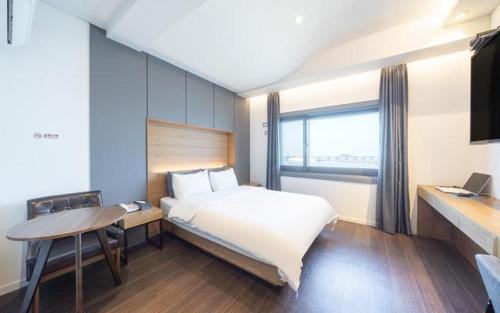 a bedroom with a bed and a desk and a window at Dangjin Dubai Hotel in Dangjin