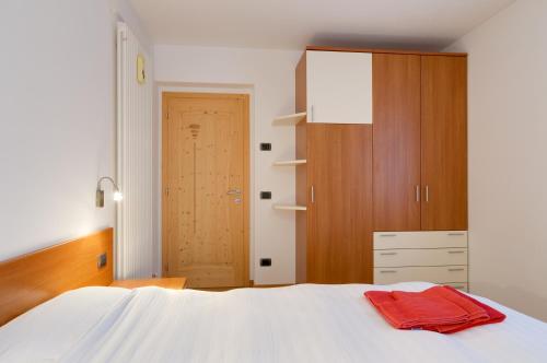 a bedroom with a white bed and a wooden cabinet at Apartments Trettel in Tesero