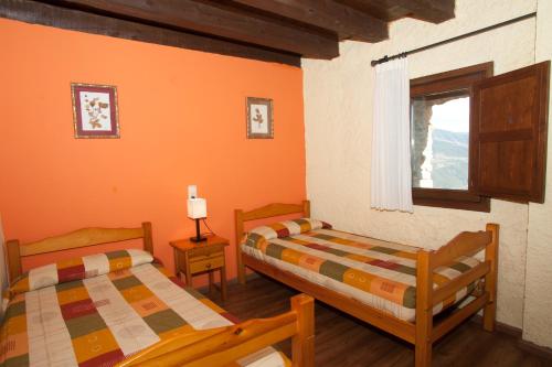 two beds in a room with orange walls at Allotjament Rural Ca L'Anton in Pujal