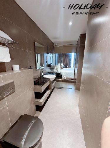 a bathroom with a toilet and a sink and a bed at Holiday Hotel Van Don in Tài Xá