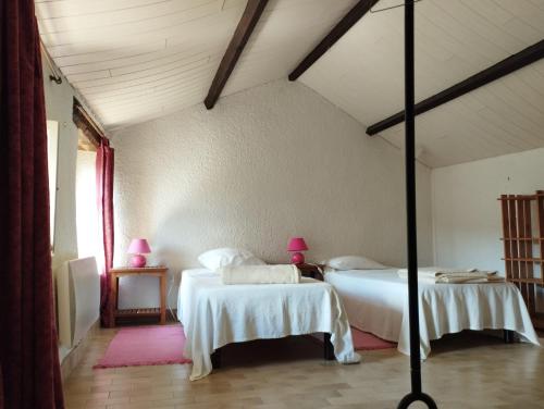 a bedroom with two beds with white sheets and pink lamps at Mas de la Petite Occitane - Cévennes sud in Saint-André-de-Majencoules