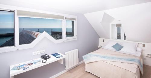 a white bedroom with a bed and a window at Hotel Atlantique in Le Palais