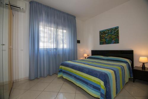 a bedroom with a bed and a window with blue curtains at Appartamenti La Mer in San Benedetto del Tronto