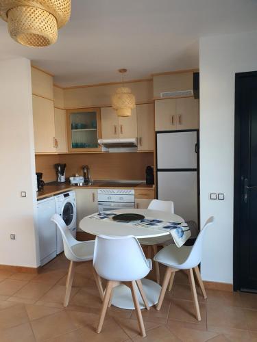a kitchen with a table and white chairs at Casa Azul in Lajares