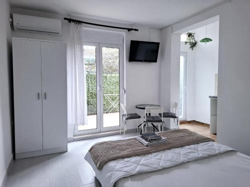 a white bedroom with a bed and a window at Apartments Kaludjerovic in Herceg-Novi