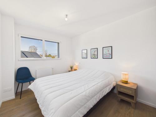 a white bedroom with a large bed and a blue chair at Superbe maison récente pour 8 avec jardin in Pléneuf-Val-André