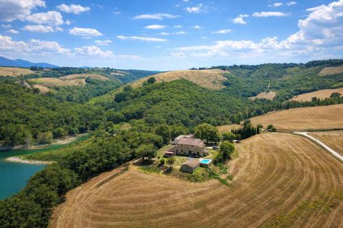 an aerial view of a house on a hill next to a river at SCAPPO IN UMBRIA, casale al lago in Corbara