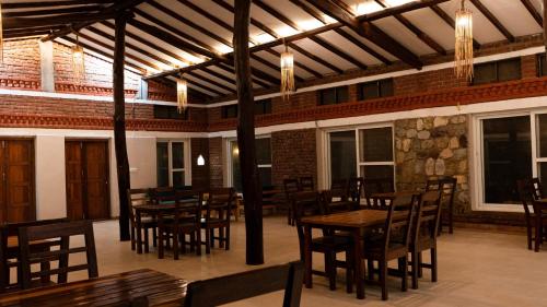 a dining room with wooden tables and chairs at Bardiya Nature Lodge in Belā