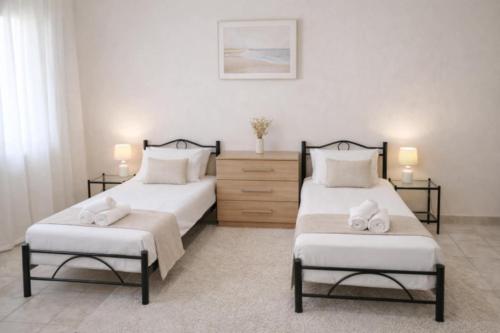 two beds in a bedroom with two chairs and a dresser at Yviome Rhodes Central Escape in Rhodes Town