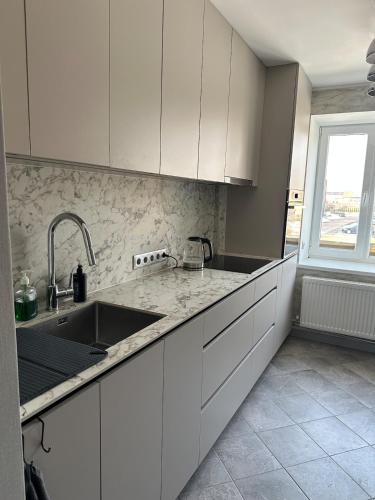 a kitchen with white cabinets and a sink and a window at Central Cozy Apartment in Ludza