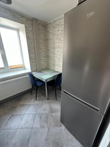 a kitchen with a refrigerator and a table and a window at Central Cozy Apartment in Ludza