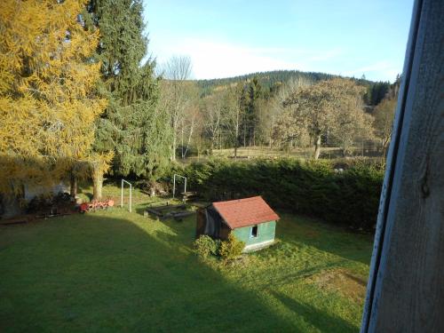 a small house in a field of grass with trees at Chata Pilka in Nové Hamry