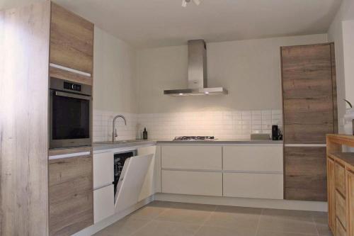 eine Küche mit weißen Geräten und Holzschränken in der Unterkunft Moderne woning met 3 kamers voor 7 personen met gratis parking in Haaltert
