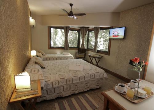 Hotel Xumec Mendoza في ميندوزا: غرفة نوم بسريرين وتلفزيون بشاشة مسطحة