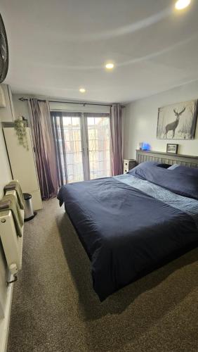 a bedroom with a large bed with a blue blanket at Hadrians wall studio in Carlisle